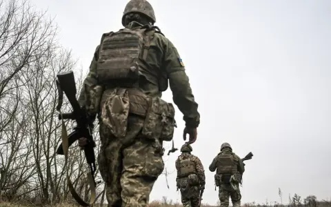 Żołnierze w ukraińskich mundurach, z karabinami, idą przez zarośla. Czy mężczyźni mogą wyjechać z Ukrainy?