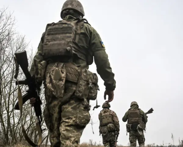 Żołnierze w ukraińskich mundurach, z karabinami, idą przez zarośla. Czy mężczyźni mogą wyjechać z Ukrainy?